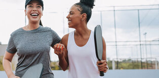 Two women playing laughing after playing pickleball